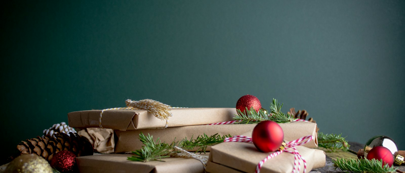 Kraft-paper wrapped gifts with red ornaments and pine branches